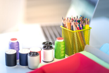 Designer sewing tools, fabric thread, colored pencils on the desk