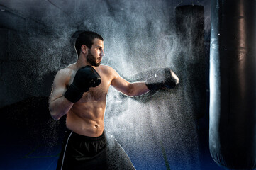 male boxer hitting a huge punching bag at a boxing studio. Man boxer training hard.