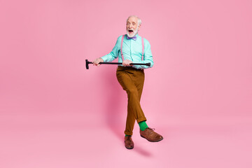 Full size photo of cool active grandpa moving dance pensioner party use walk stick raise leg wear mint shirt suspenders bow tie trousers shoes green socks isolated pink pastel background