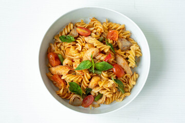 Close up Tasty Gourmet Spicy Pasta with Tomato and Herbs on a White Plate, Served on Top of a white wooden  Table.