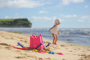 Summer vacation. Adorable toddler girl playing with beach toys on the sandy beach.