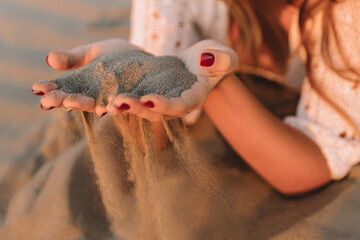 Sand in hands of girl on the beach
