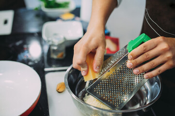 Chef grating cheese, chef hand grating parmesan cheese with grater, Chef rubbing cheese on a grater, close up