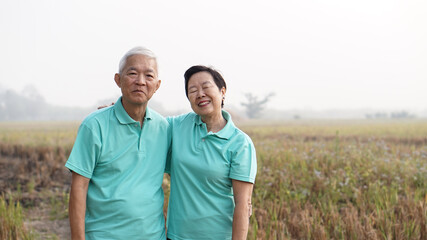 Asian elderly stand with their farm after harvested at the end of season
