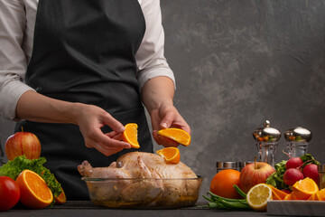 A cook prepares a chicken by decorating it with fruit for a festive table, menu or homemade recipes.