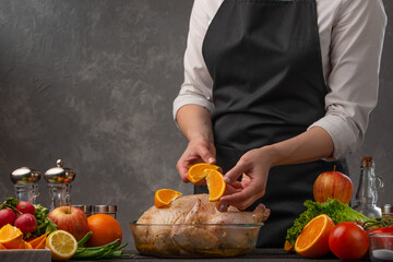 A cook prepares a chicken by decorating it with fruit for a festive table, menu or homemade recipes.