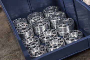 Cylindrical steel metal part with round holes made on lathe in blue case. Metal industry products, workpieces. Steel products to automotive industry. Billet obtained on lathe from steel and cast iron