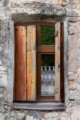 Vintage window with wooden shutters in an ancient stone house.