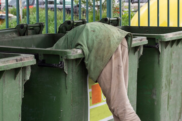 A homeless person leaned into a trash can in search of some food.