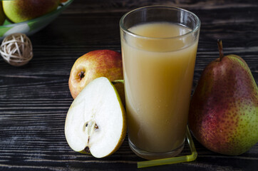 a glass of pear juice and juicy pears on a dark wooden background close up