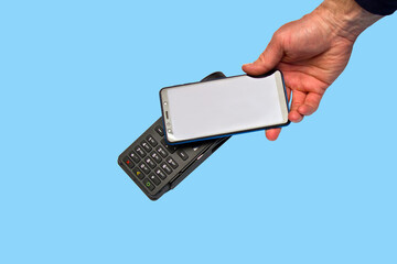 Male hand using contactless payment terminal with smartphone on blue background