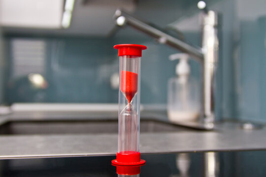 Man washes his hands with soap and uses an hourglass to measure hand washing time