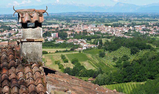 Rustic chimney of  a chalet in the hills above Cividale del Friuli, whose townscape can be seen in the background.