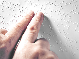 Hands of a blind person reading some braille text touching the relief. Horizontal