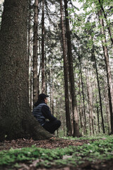 Traveler man relaxing in forest with photo camera, backpack. Travel lifestyle concept vacations outdoor.