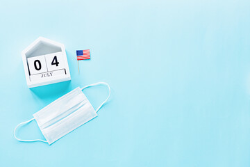 July 4th. USA flag and medical mask on blue background. Independence Day Of America 2020 during coronavirus covid-19 pandemic quarantine. Flat lay, top view, template