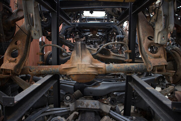 Close up shot to a rusty car axle. More appear in background. Awaiting to be used again or to recycling. In a vehicle graveyard. Kozani, Greece.