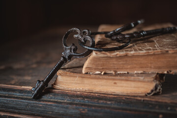 old vintage keys on an old battered book, wooden background.