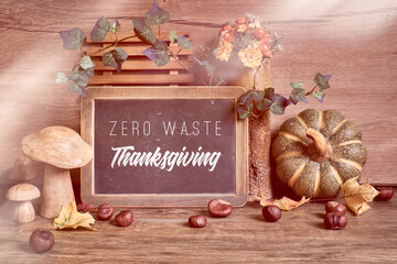 Autumn rustic decorations, text "Zero Waste Autumn" on a black chalk board. Natural Fall Thanksgiving. Autumn leaves, ceramic pumpkin, decorative wooden mushrooms. Eco friendly zero waste decor.