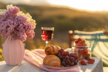 French style romantic summer picnic. Flat glasses of rose wine, fresh strawberries, croissants, brie cheese.