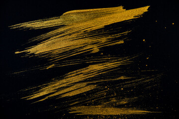 strokes with golden paint brush on black paper.