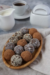 chocolate cake pops on wooden plate on light table with a cup of coffee and milk