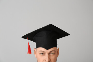 Man in graduation hat on grey background