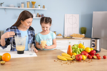 Mother and little daughter with healthy smoothie in kitchen