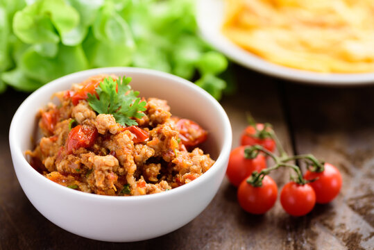 Northern Thai food (Nam Prik Ong), spicy chili minced pork with tomatoes in a bowl on wooden background