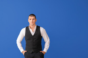 Handsome young man in elegant suit on color background