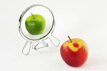 Red apple looking in the mirror and seeing itself as a green apple - Concept of daltonism and color...