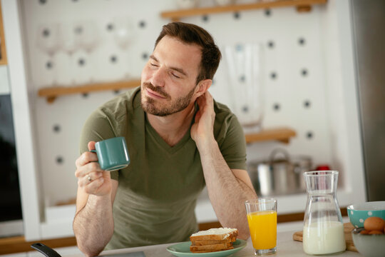 Handsome man preparing breakfast at home. Young man drinking coffee in kitchen.	
