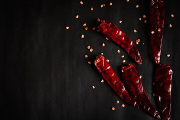Dried red chili or chili cayenne pepper with chili seeds sprinkled over it isolated on black...