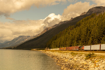 Train transporting goods passing along a mountain range and a lake