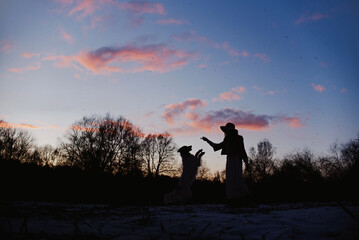 silhouettes of young woman and dog outdoors in winter