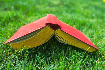 Open red book on the green lawn grass outside