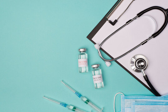 Coronavirus vaccine test lab concept. Doctor's desktop office workplace. Top above overhead view photo of vaccine vial masks stethoscope shots clipboard side isolated on blue turquoise background