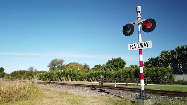 4k stationary locked off shot with sound of warning signal and flashing red lights at roadside railway crossing to stop traffic of approaching train,north island,New Zealand