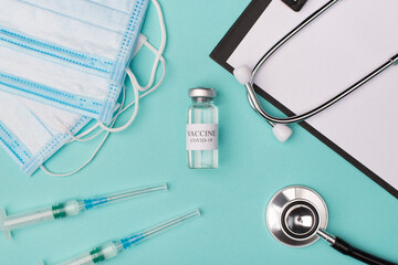 New coronavirus vaccine testing prescribing medicine concept. Top above overhead view photo of vaccine vial masks stethoscope shots and clipboard isolated on blue background