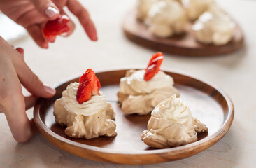the process of creating Pavlova dessert, decorating the meringue with strawberries