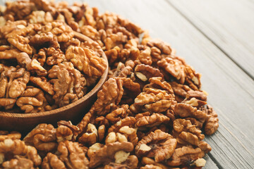 Bowl with tasty walnuts on wooden background