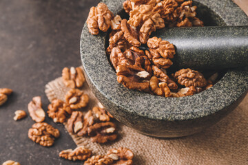 Mortar and pestle with tasty walnuts on table