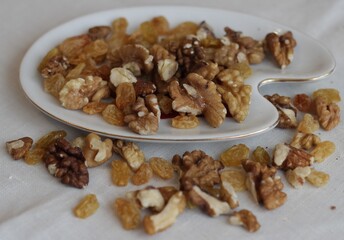 Plate with walnuts and raisins on a table on a napkin