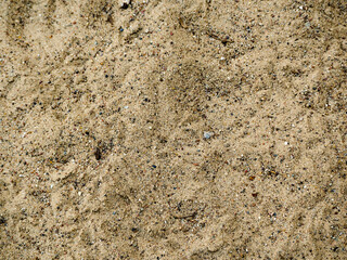 large grains of sand with small stones close-up . dark sand background