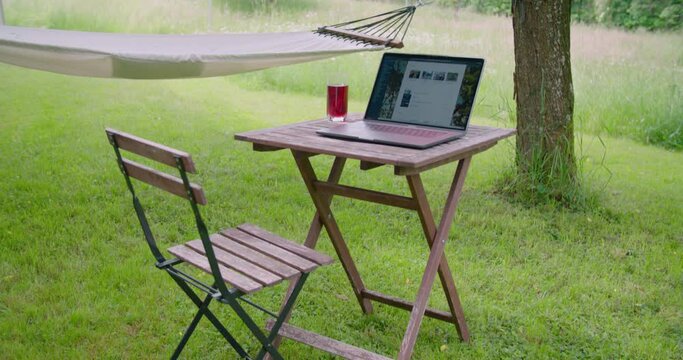 Homeoffice setting with laptop on table in garden next to hammock