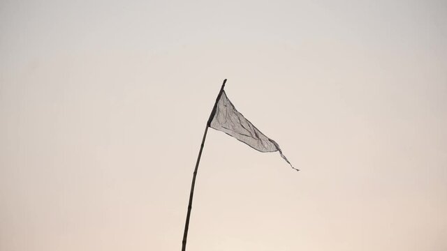 A trigonal flag waving in wind up the sky attached to a stick in front of white isolated background