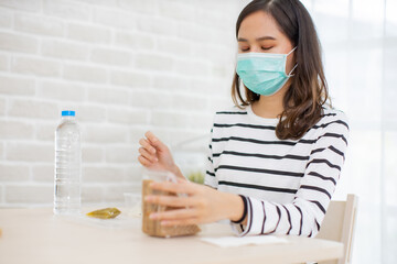 Young Asian  woman sitting separated in restaurant or home  eating food with table protect...