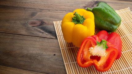 red, green and yellow sweet bell peppers on wood background, paprika, organic vegetables
