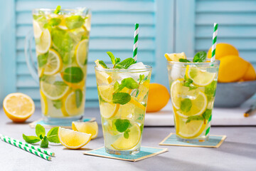 Lemonade, lemon, mint cocktail in glasses and jug. Blue background. © annapustynnikova