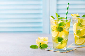 Lemonade, lemon ice tea, mint cocktail in glass. Blue background. Close up. Copy space.